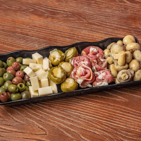 Nonna's Italian Deli & Market antipasto platter with olives, cheese, stuffed peppers, prosciutto, and mushrooms.