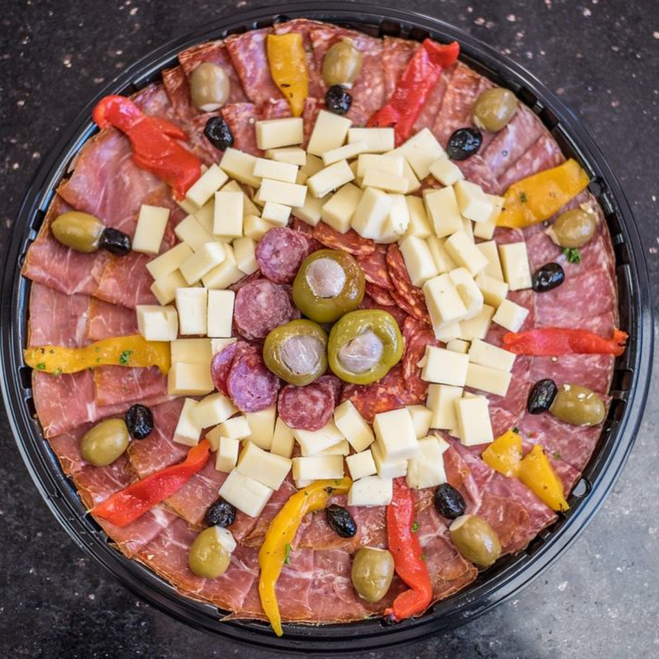 A large Nonna's Italian Deli & Market charcuterie platter with meats, cheeses, olives, and peppers.