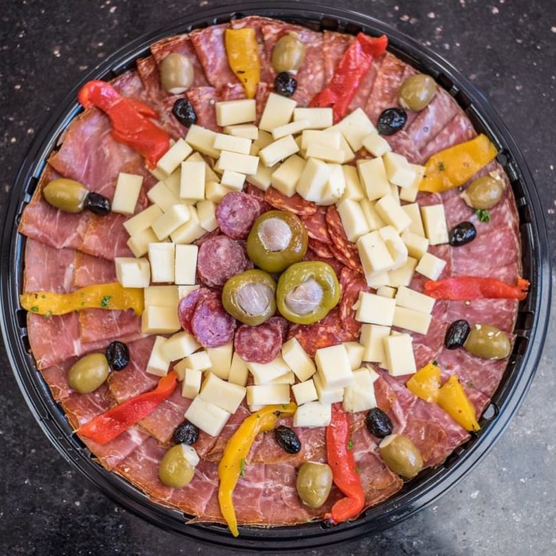 A large Nonna's Italian Deli & Market charcuterie platter with meats, cheeses, olives, and peppers.