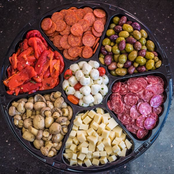An Italian antipasto platter with pepperoni, salami, olives, roasted peppers, mushrooms, mozzarella, and cheese cubes.